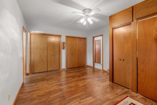 3820 8th St, Owatonna, MN 55060 - unfurnished bedroom featuring two closets, wood finished floors, and ceiling fan