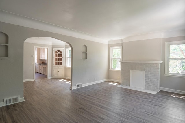 3410 Dupont Ave N, Minneapolis, MN 55412 - unfurnished living room featuring healthy amount of natural light, a fireplace, dark wood-style floors, and arched walkways