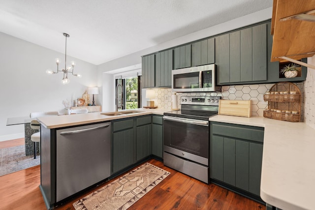 6502 Lancaster Ln N, Maple Grove, MN 55369 - kitchen with appliances with stainless steel finishes, a peninsula, tasteful backsplash, light countertops, and dark wood-style floors