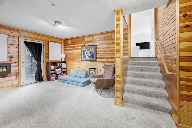6502 Lancaster Ln N, Maple Grove, MN 55369 - carpeted living room featuring wooden walls, stairs, a textured ceiling, and a glass covered fireplace