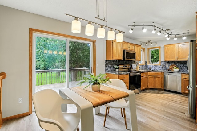 11883 Marigold Way, Lindstrom, MN 55045 - kitchen with appliances with stainless steel finishes, decorative backsplash, light wood-style flooring, hanging light fixtures, and dark stone counters