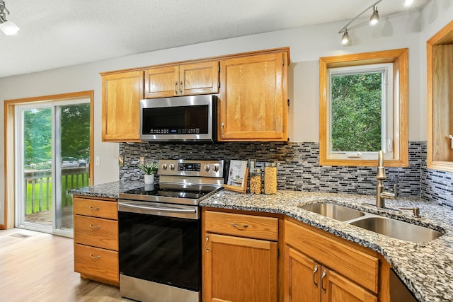 11883 Marigold Way, Lindstrom, MN 55045 - kitchen featuring appliances with stainless steel finishes, rail lighting, light stone countertops, backsplash, and light wood-style floors