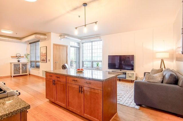 521 2nd St SE Unit 307, Minneapolis, MN 55414 - kitchen featuring brown cabinetry, light wood-style floors, light stone counters, and hanging light fixtures