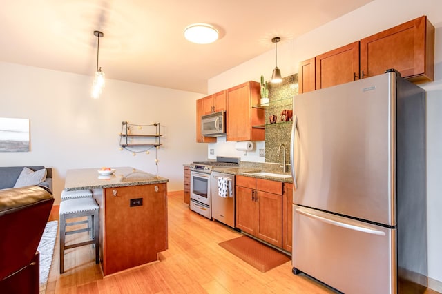 521 2nd St SE Unit 307, Minneapolis, MN 55414 - kitchen featuring appliances with stainless steel finishes, light wood-style flooring, open shelves, decorative light fixtures, and brown cabinetry