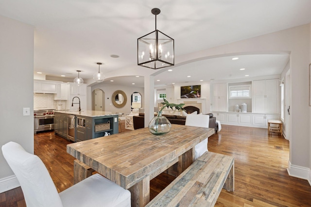 4622 Drexel Ave, Edina, MN 55424 - dining space featuring arched walkways, dark wood finished floors, recessed lighting, a fireplace, and a chandelier