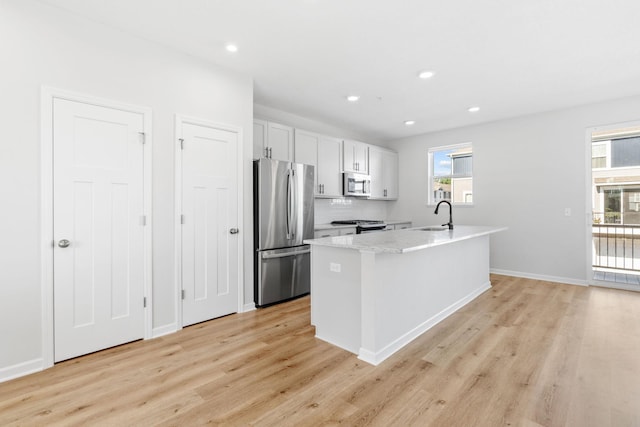 7614 Connie Ln, Inver Grove Heights, MN 55076 - kitchen with appliances with stainless steel finishes, light wood-type flooring, recessed lighting, white cabinets, and a kitchen island with sink