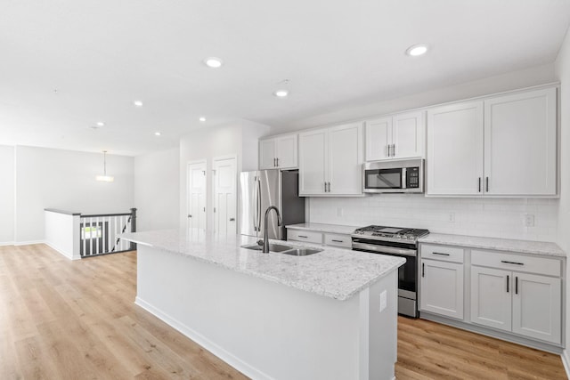 7614 Connie Ln, Inver Grove Heights, MN 55076 - kitchen featuring appliances with stainless steel finishes, tasteful backsplash, an island with sink, light wood-style floors, and recessed lighting