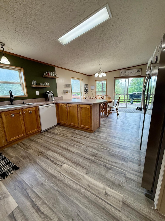 656 22nd Ave NW, Baudette Twp, MN 56623 - kitchen with dishwasher, a textured ceiling, brown cabinetry, freestanding refrigerator, and a peninsula