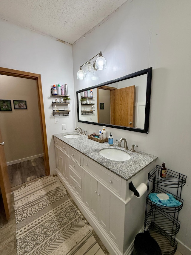 656 22nd Ave NW, Baudette Twp, MN 56623 - full bathroom featuring double vanity, a textured ceiling, and wood finished floors
