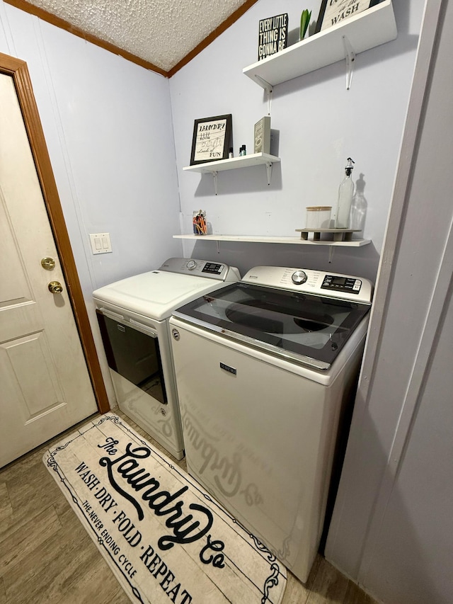 656 22nd Ave NW, Baudette Twp, MN 56623 - washroom with washing machine and clothes dryer, ornamental molding, a textured ceiling, and light wood-type flooring