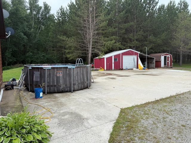 656 22nd Ave NW, Baudette Twp, MN 56623 - view of patio / terrace with a detached garage, a storage shed, an outdoor pool, and a forest view