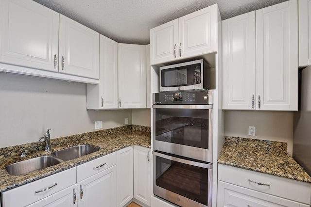 14170 Westridge Dr, Eden Prairie, MN 55347 - kitchen featuring stainless steel appliances, white cabinets, dark stone counters, and a textured ceiling