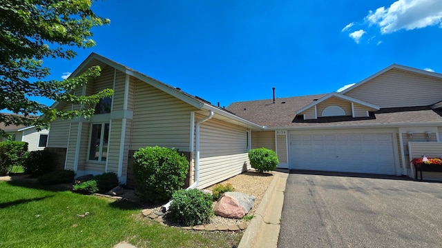 9136 Windsor Ter, Brooklyn Park, MN 55443 - view of front of property with a garage, asphalt driveway, roof with shingles, and a front lawn