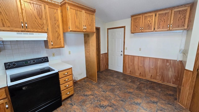 9136 Windsor Ter, Brooklyn Park, MN 55443 - kitchen featuring electric range, under cabinet range hood, brown cabinets, a wainscoted wall, and wood walls