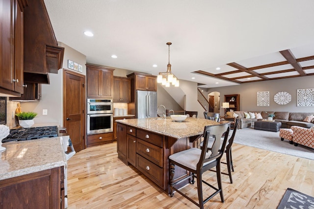 7461 Merrimac Ln N, Maple Grove, MN 55311 - kitchen with appliances with stainless steel finishes, light wood-style flooring, a kitchen breakfast bar, recessed lighting, and pendant lighting