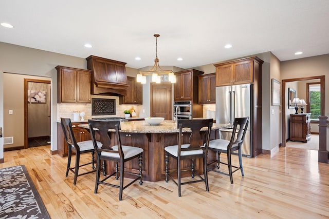 7461 Merrimac Ln N, Maple Grove, MN 55311 - kitchen with stainless steel appliances, premium range hood, decorative backsplash, a center island with sink, and light wood finished floors