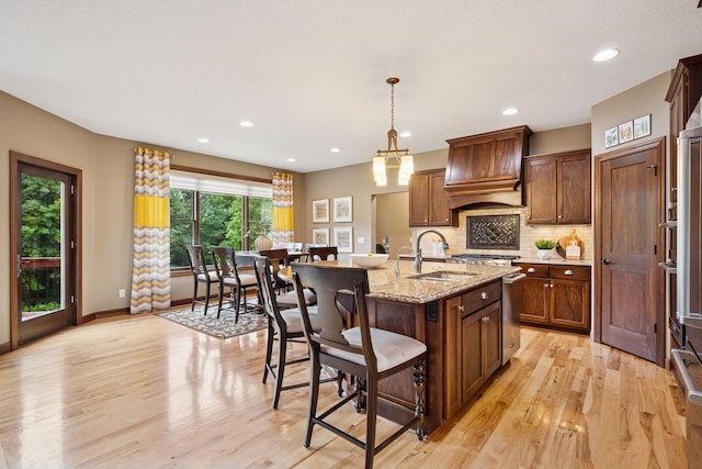 7461 Merrimac Ln N, Maple Grove, MN 55311 - kitchen with custom exhaust hood, light wood finished floors, a breakfast bar, backsplash, and recessed lighting