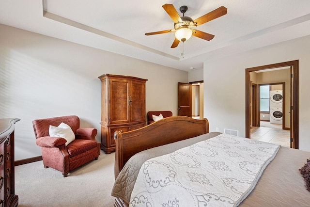 7461 Merrimac Ln N, Maple Grove, MN 55311 - bedroom with stacked washer / drying machine, a tray ceiling, a ceiling fan, and light colored carpet