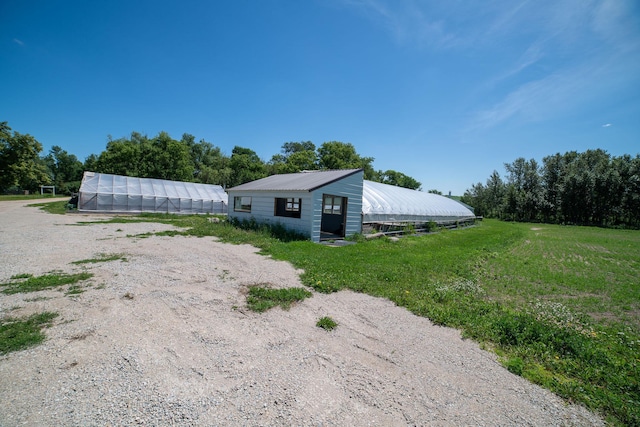 43724 County Highway 19, Blowers Twp, MN 56477 - view of side of property with a greenhouse, an outbuilding, a metal roof, and a yard