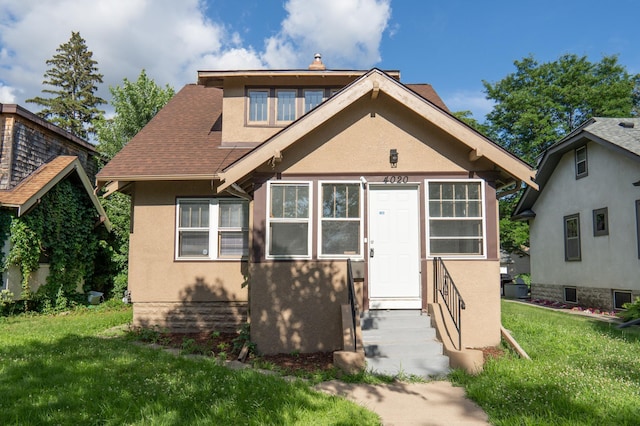 4020 Emerson Ave N, Minneapolis, MN 55412 - bungalow featuring stucco siding, a front lawn, roof with shingles, and entry steps