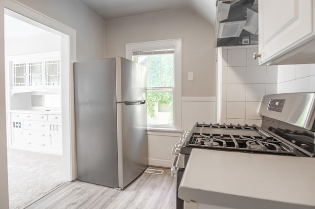 4020 Emerson Ave N, Minneapolis, MN 55412 - kitchen featuring appliances with stainless steel finishes, wall chimney range hood, light wood-style flooring, plenty of natural light, and a wainscoted wall