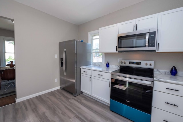 1702 Minnehaha Ave W, Saint Paul, MN 55104 - kitchen featuring appliances with stainless steel finishes, light wood-type flooring, white cabinets, and light stone countertops
