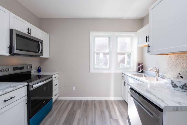 1702 Minnehaha Ave W, Saint Paul, MN 55104 - kitchen with stainless steel appliances, light wood-style flooring, white cabinets, and light stone counters