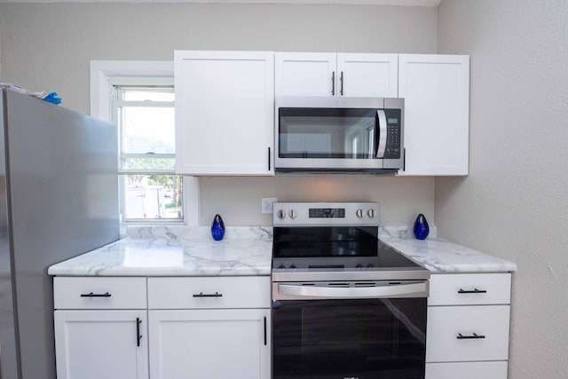 1702 Minnehaha Ave W, Saint Paul, MN 55104 - kitchen featuring appliances with stainless steel finishes, white cabinets, light stone counters, and a textured wall