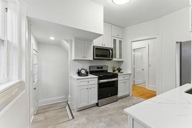 3148 Bryant Ave S, Minneapolis, MN 55408 - kitchen with appliances with stainless steel finishes, glass insert cabinets, white cabinets, light stone counters, and tasteful backsplash
