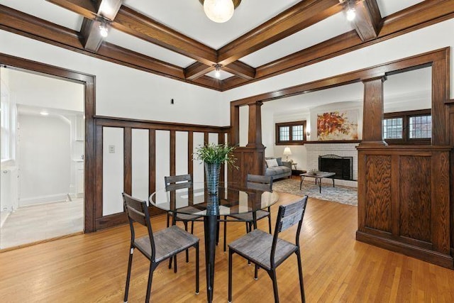 3148 Bryant Ave S, Minneapolis, MN 55408 - dining room with decorative columns, coffered ceiling, beamed ceiling, a brick fireplace, and light wood-type flooring