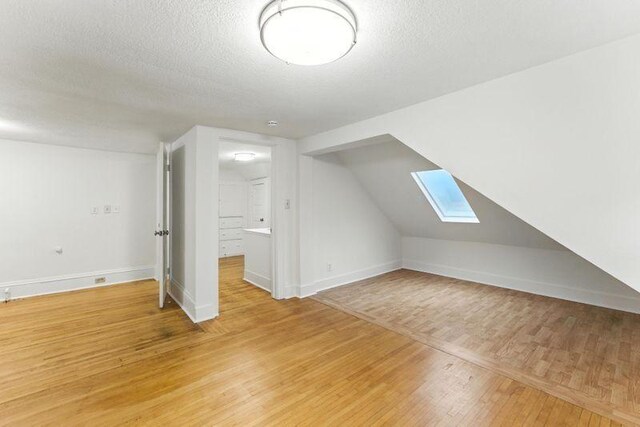 3148 Bryant Ave S, Minneapolis, MN 55408 - bonus room with a skylight, light wood finished floors, and a textured ceiling