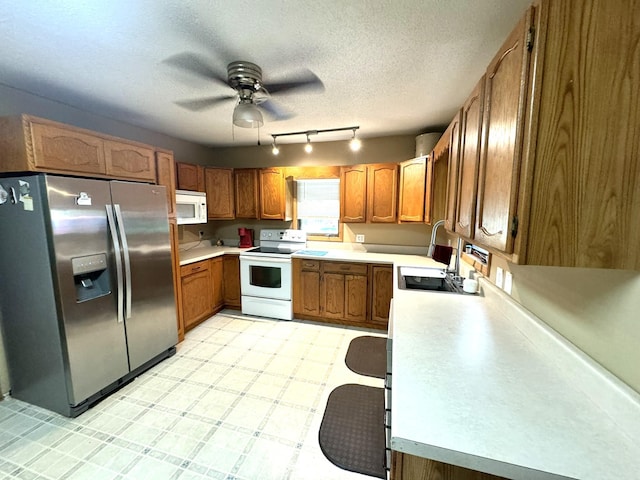 600 Gilbert Ave S, Park Rapids, MN 56470 - kitchen featuring white appliances, brown cabinetry, rail lighting, ceiling fan, and light countertops