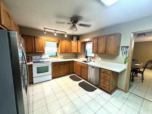 600 Gilbert Ave S, Park Rapids, MN 56470 - kitchen featuring stainless steel appliances, a textured ceiling, a ceiling fan, light countertops, and brown cabinets
