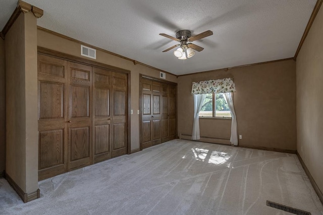 41072 280th St, Arlington Twp, MN 55307 - unfurnished bedroom featuring light carpet, multiple closets, ornamental molding, a textured ceiling, and baseboard heating