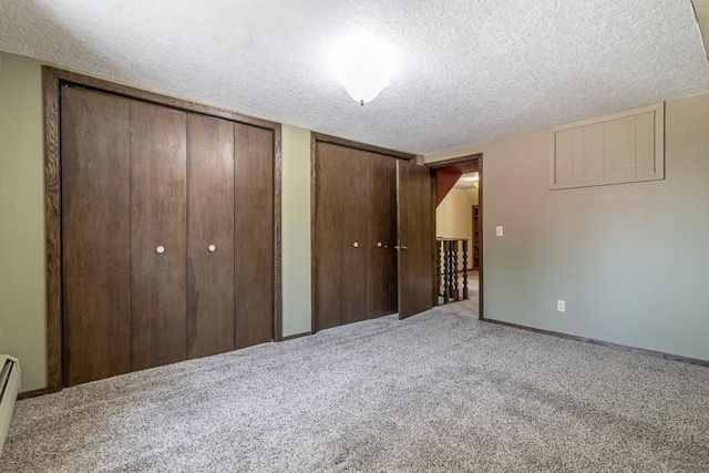 41072 280th St, Arlington Twp, MN 55307 - unfurnished bedroom featuring a textured ceiling, two closets, carpet flooring, and baseboard heating