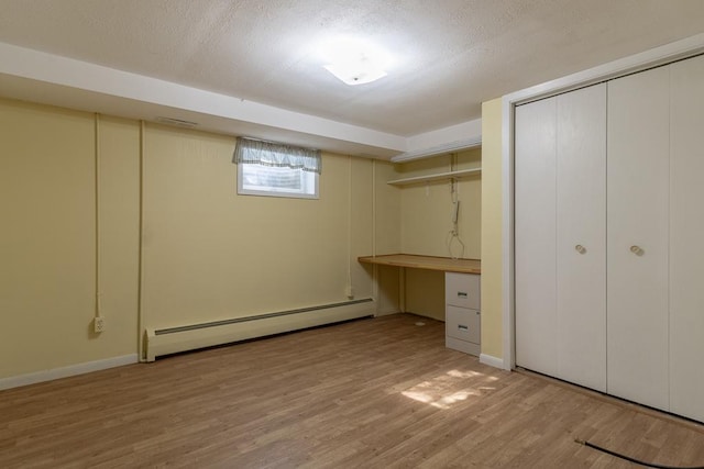 41072 280th St, Arlington Twp, MN 55307 - basement featuring a baseboard radiator, light wood-style floors, a textured ceiling, and a desk