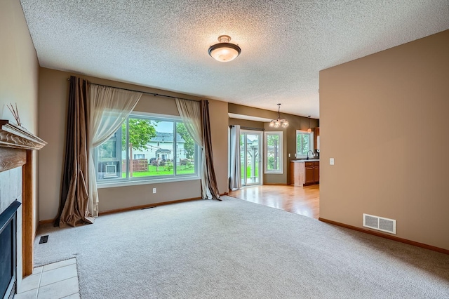 2907 Asarum Ct, Shakopee, MN 55379 - unfurnished living room with light carpet, a tiled fireplace, a chandelier, and a textured ceiling