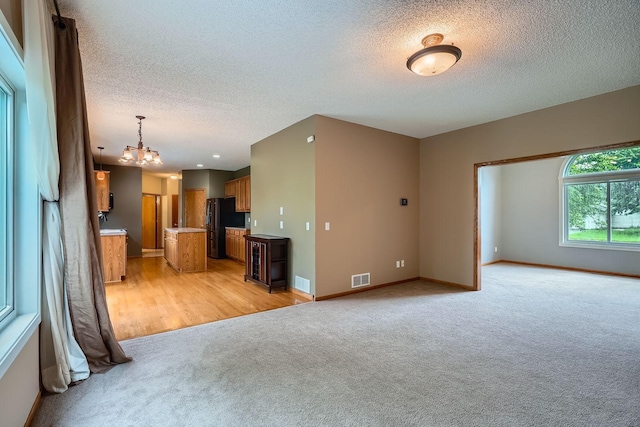 2907 Asarum Ct, Shakopee, MN 55379 - unfurnished living room with a chandelier, light colored carpet, and a textured ceiling