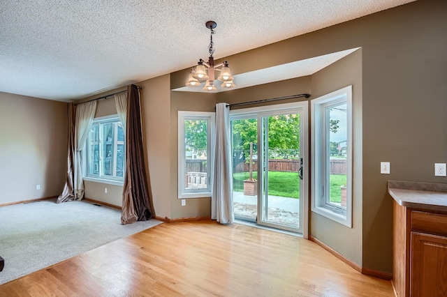 2907 Asarum Ct, Shakopee, MN 55379 - unfurnished dining area with light wood-style flooring, a chandelier, and a textured ceiling