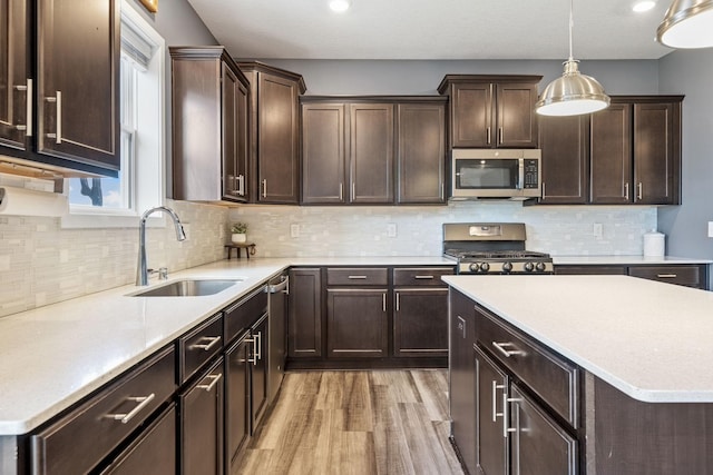 5027 Jansen Ave NE, Saint Michael, MN 55376 - kitchen featuring appliances with stainless steel finishes, light wood-style flooring, dark brown cabinets, pendant lighting, and light countertops