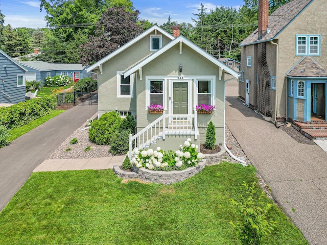 500 Otis Ave, Saint Paul, MN 55104 - bungalow featuring stucco siding, driveway, a front lawn, and a chimney