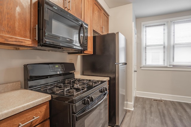 3919 Dupont Ave N, Minneapolis, MN 55412 - kitchen featuring black appliances, brown cabinetry, wood finished floors, and light countertops