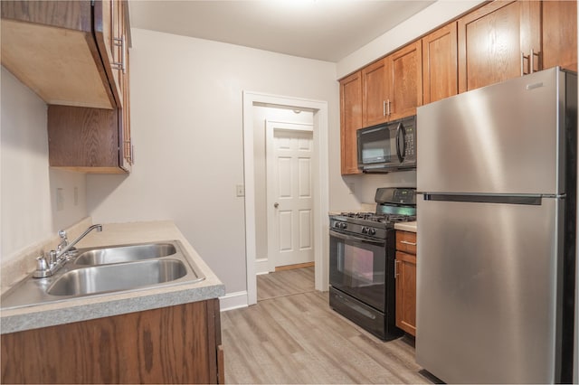 3919 Dupont Ave N, Minneapolis, MN 55412 - kitchen with black appliances, light wood-type flooring, light countertops, and brown cabinets