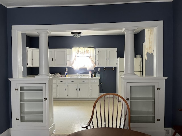 1157 6th Ave S, Windom, MN 56101 - kitchen featuring decorative columns, white cabinetry, crown molding, light countertops, and light wood finished floors