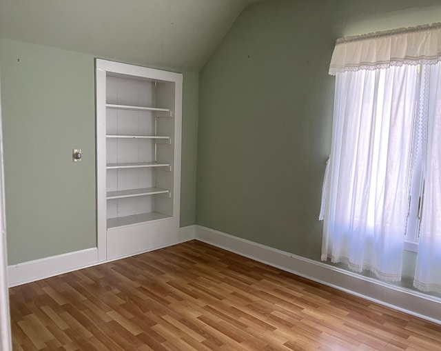 1157 6th Ave S, Windom, MN 56101 - empty room featuring built in shelves, vaulted ceiling, and wood finished floors