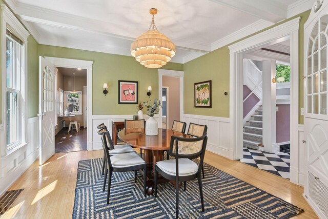 2432 Pleasant Ave, Minneapolis, MN 55404 - dining room with light wood-style floors, a chandelier, stairs, wainscoting, and a decorative wall