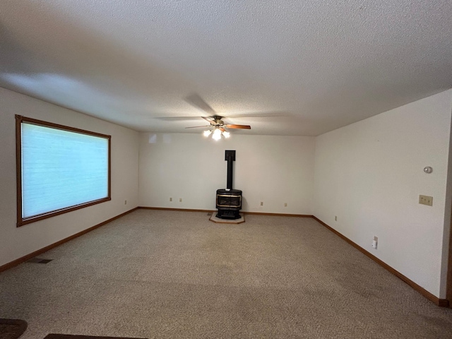 353 River Dr, Park Rapids, MN 56470 - unfurnished room featuring a wood stove, light carpet, ceiling fan, and a textured ceiling