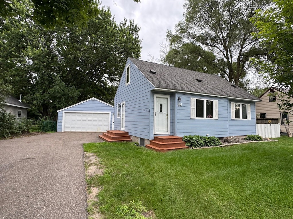 44 Center Rd, Circle Pines, MN 55014 - view of front of house with an outbuilding, a garage, a shingled roof, and a front lawn