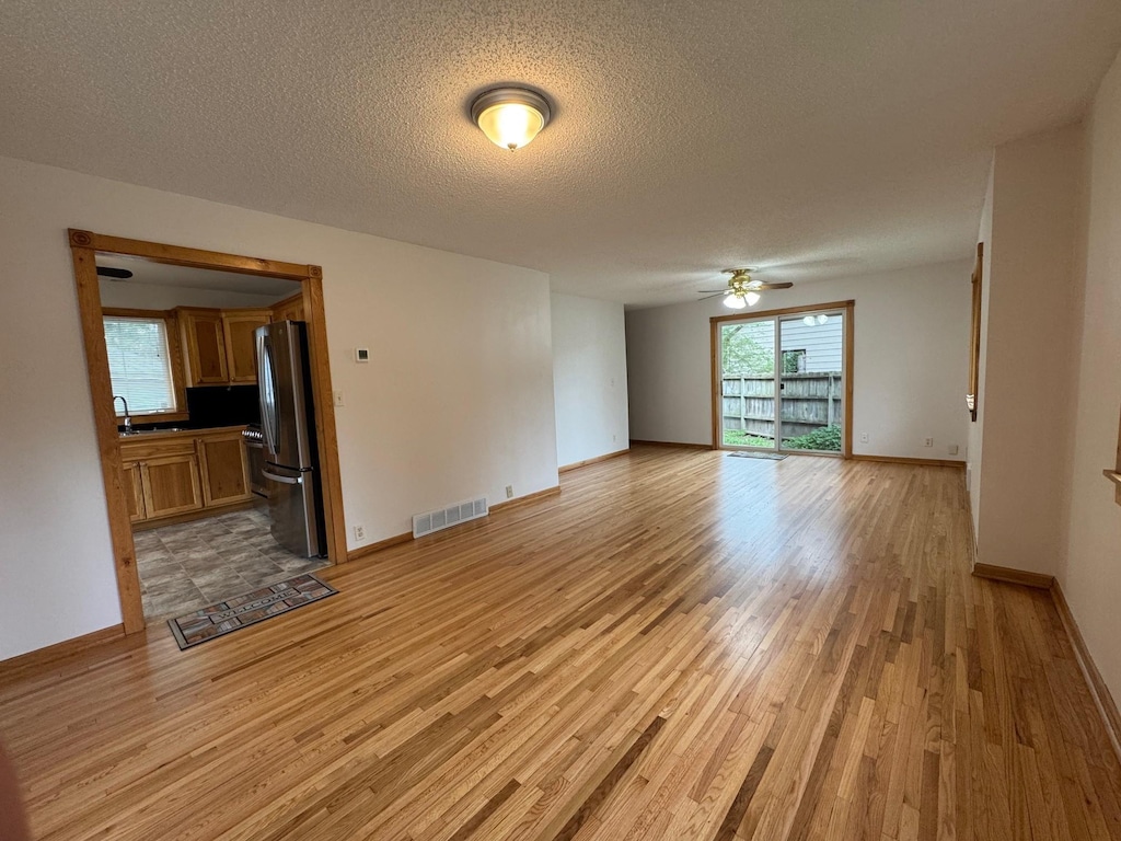 44 Center Rd, Circle Pines, MN 55014 - unfurnished living room featuring light wood-style floors, a ceiling fan, and a textured ceiling