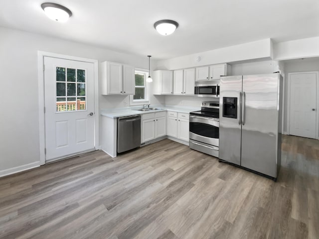206 Winona St W, West Saint Paul, MN 55118 - kitchen featuring stainless steel appliances, light countertops, white cabinetry, light wood-style flooring, and decorative light fixtures